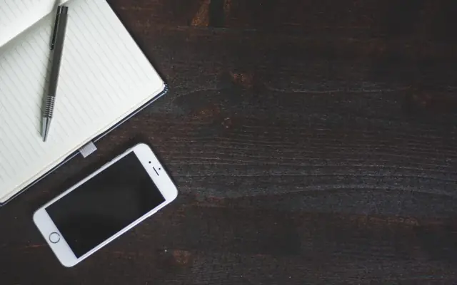 Smartphone and notebook on a dark desk